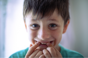 boy holding mouth and teeth smiling