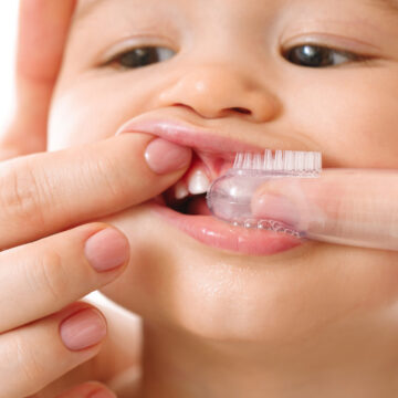 Mother gently brooshing her small child teeth.