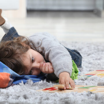 Toddler sucking thumb while playing at home